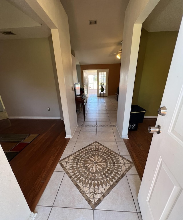 hallway with baseboards, light tile patterned floors, and visible vents