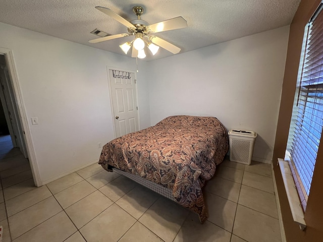 bedroom with baseboards, light tile patterned flooring, visible vents, and a textured ceiling