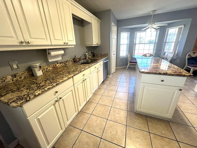 kitchen with stainless steel dishwasher, a center island, light tile patterned flooring, ceiling fan, and a sink