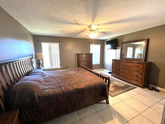 tiled bedroom with ceiling fan and a textured ceiling