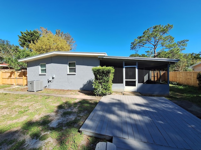 rear view of property featuring a sunroom, a wooden deck, and central air condition unit