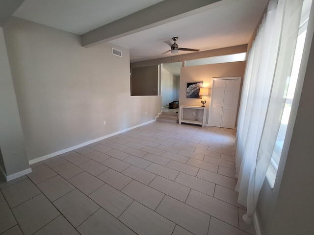 unfurnished living room with beamed ceiling, plenty of natural light, light tile patterned flooring, and ceiling fan