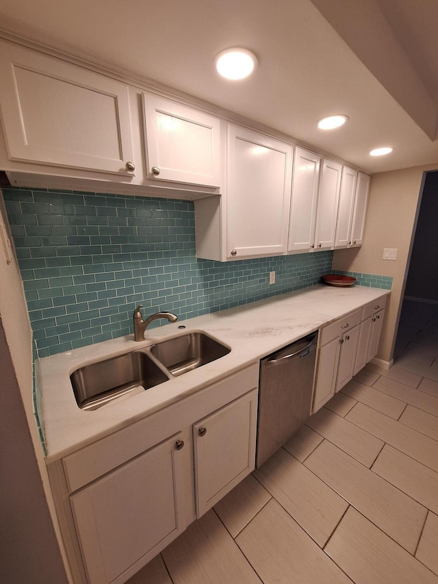 kitchen featuring stainless steel dishwasher, white cabinetry, sink, and tasteful backsplash