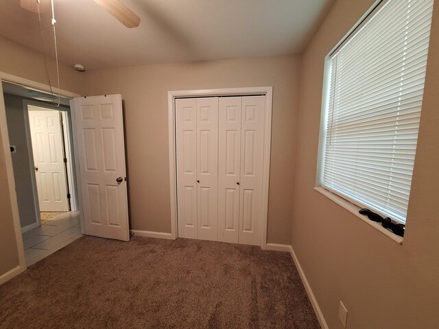 unfurnished bedroom with carpet, a closet, and ceiling fan