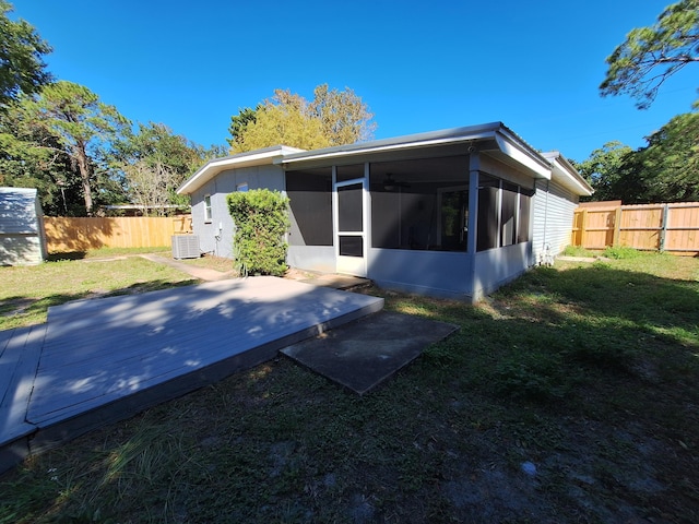 rear view of property featuring a yard, a deck, cooling unit, and a sunroom