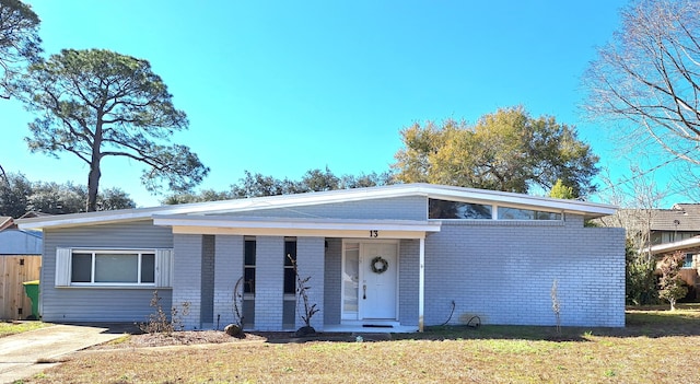 mid-century home with a front yard and brick siding