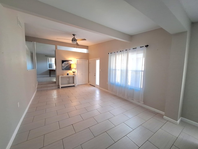 interior space with ceiling fan, beamed ceiling, light tile patterned flooring, and baseboards