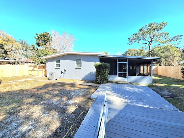 rear view of house with central air condition unit, a sunroom, a fenced backyard, and a deck