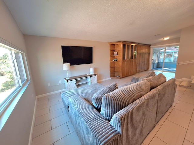 living area with light tile patterned floors, baseboards, and a textured ceiling