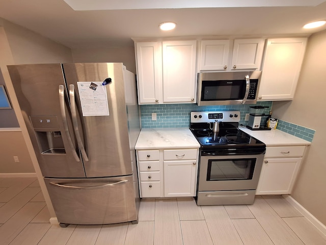 kitchen featuring appliances with stainless steel finishes, white cabinets, backsplash, and baseboards