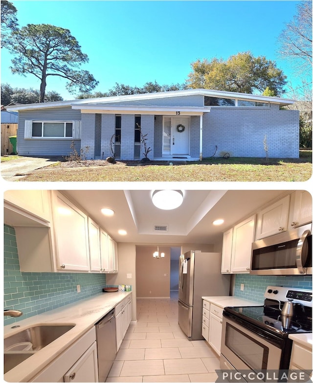 kitchen featuring a tray ceiling, visible vents, appliances with stainless steel finishes, white cabinets, and a sink