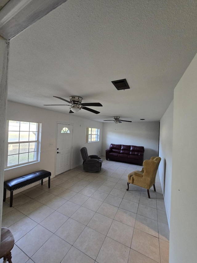 unfurnished living room featuring ceiling fan, a textured ceiling, and light tile patterned flooring