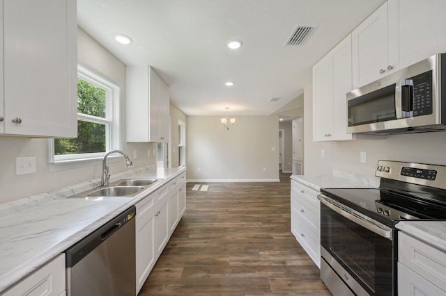 kitchen with dark wood-type flooring, white cabinetry, light stone counters, and stainless steel appliances