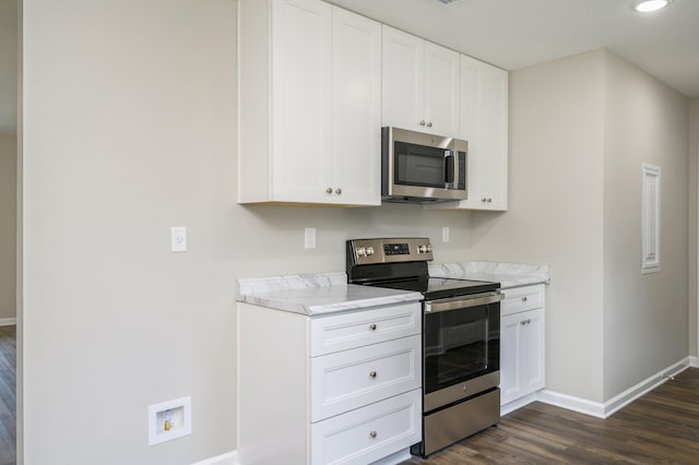 kitchen featuring appliances with stainless steel finishes, white cabinetry, light stone countertops, and dark hardwood / wood-style floors