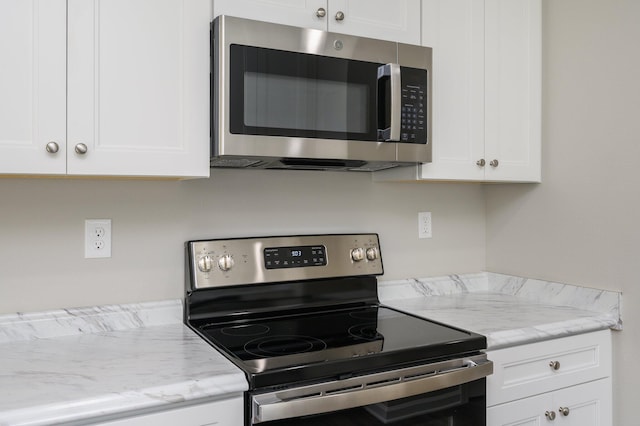 kitchen featuring appliances with stainless steel finishes, white cabinets, and light stone countertops