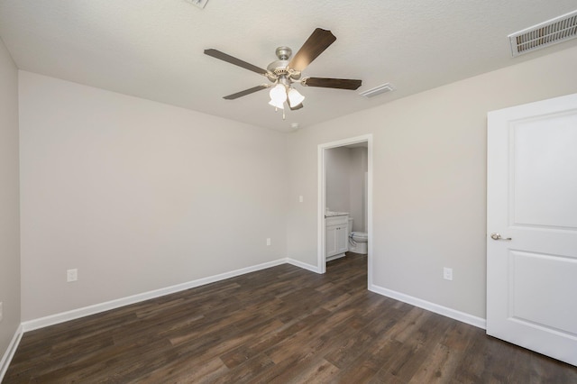 unfurnished bedroom with ceiling fan, a textured ceiling, dark hardwood / wood-style flooring, and ensuite bath