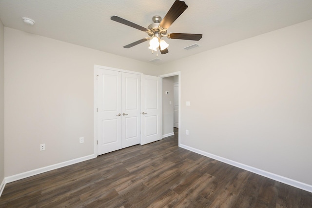 unfurnished bedroom featuring a closet, dark wood-type flooring, and ceiling fan