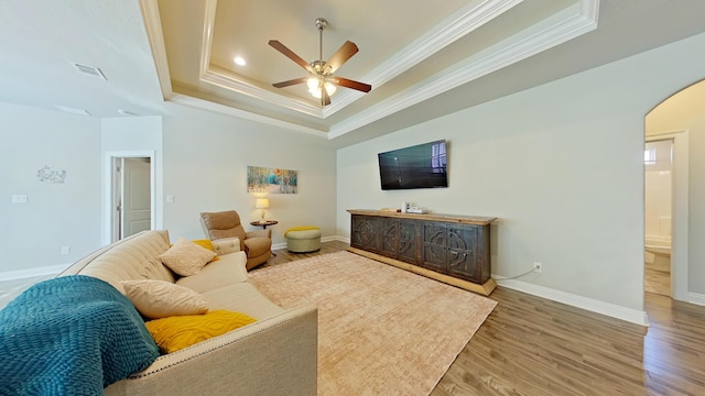 living room with ceiling fan, crown molding, a tray ceiling, and hardwood / wood-style floors