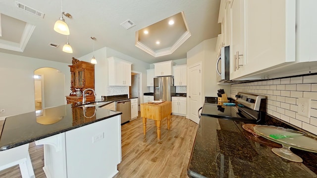 kitchen featuring stainless steel appliances, a tray ceiling, pendant lighting, white cabinets, and sink