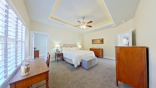 bedroom with ceiling fan, a tray ceiling, and carpet flooring