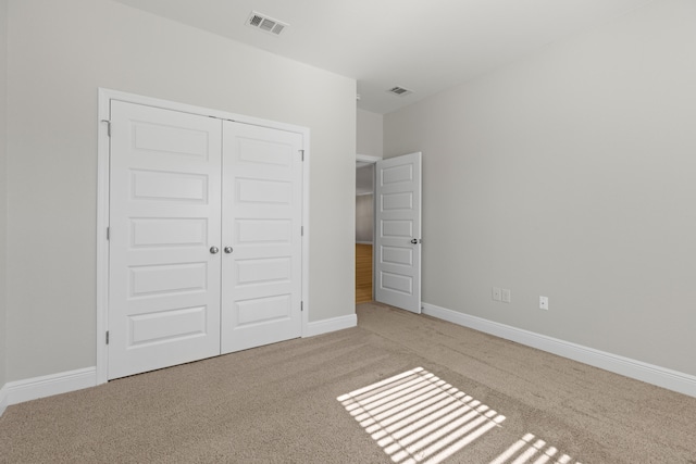 unfurnished bedroom featuring light colored carpet and a closet