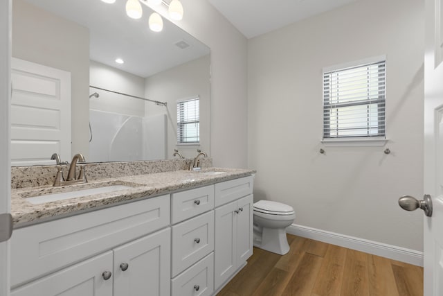 bathroom with toilet, vanity, wood-type flooring, and walk in shower