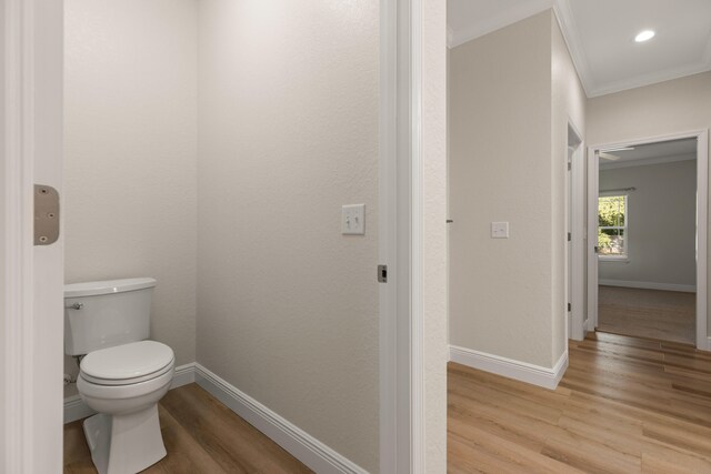 bathroom with hardwood / wood-style flooring, toilet, and ornamental molding