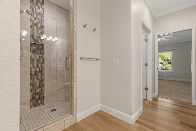 bathroom featuring hardwood / wood-style floors, ceiling fan, an enclosed shower, and crown molding