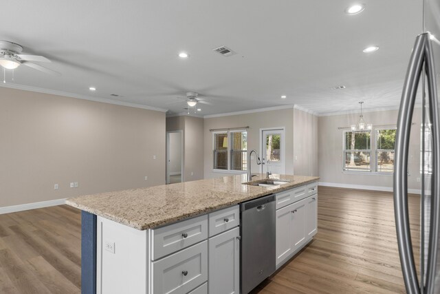 kitchen with appliances with stainless steel finishes, ornamental molding, sink, white cabinetry, and an island with sink