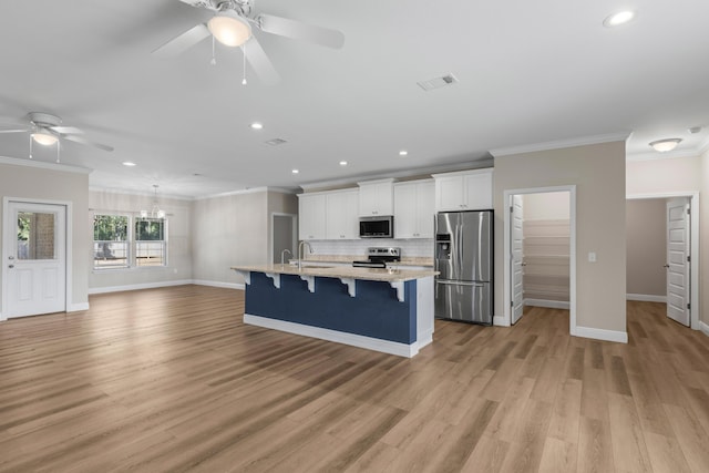 kitchen with a center island with sink, a kitchen breakfast bar, sink, appliances with stainless steel finishes, and white cabinetry