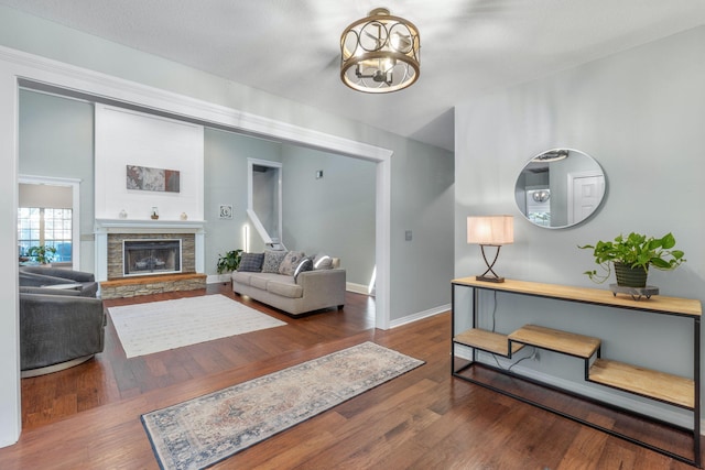 living room featuring dark wood-type flooring and a stone fireplace