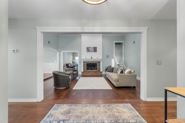 living room featuring a stone fireplace and dark hardwood / wood-style floors