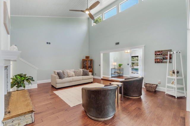 living room with a fireplace, wood-type flooring, high vaulted ceiling, and ceiling fan