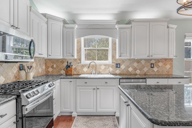 kitchen featuring tasteful backsplash, wood-type flooring, appliances with stainless steel finishes, sink, and dark stone counters