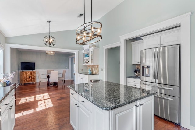 kitchen with lofted ceiling, a kitchen island, stainless steel refrigerator with ice dispenser, pendant lighting, and white cabinets