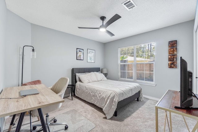 bedroom with a textured ceiling, light colored carpet, and ceiling fan