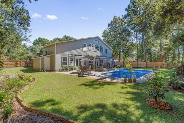 rear view of property featuring a patio, a fenced in pool, and a yard