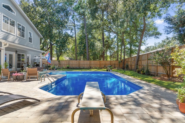 view of swimming pool featuring a patio and a diving board