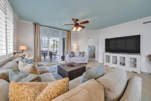 living room with ceiling fan, plenty of natural light, and ornamental molding