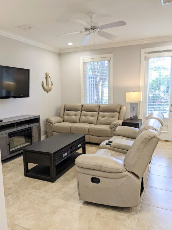 living room featuring a wealth of natural light, crown molding, light tile patterned floors, and ceiling fan