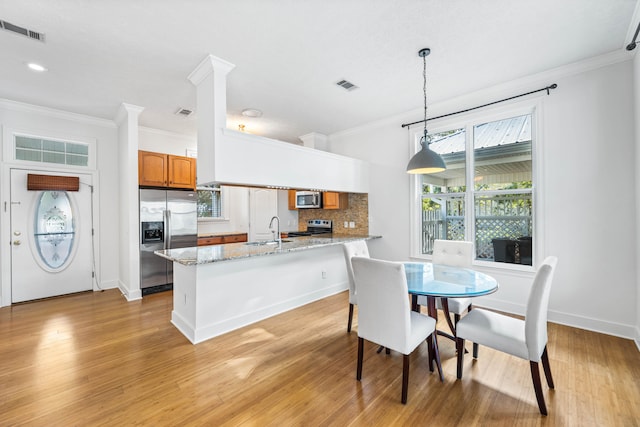 dining area featuring sink, light hardwood / wood-style flooring, and ornamental molding