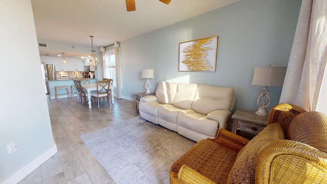 living room featuring light hardwood / wood-style floors and ceiling fan with notable chandelier