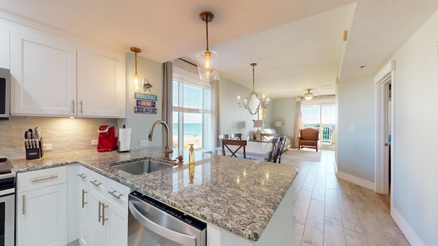 kitchen with sink, light wood-type flooring, hanging light fixtures, stainless steel appliances, and white cabinets