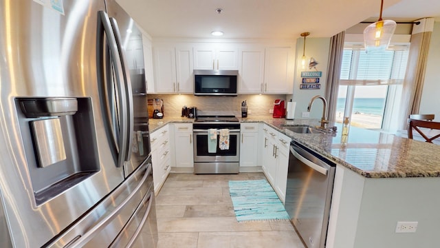 kitchen featuring hanging light fixtures, sink, white cabinetry, appliances with stainless steel finishes, and a water view