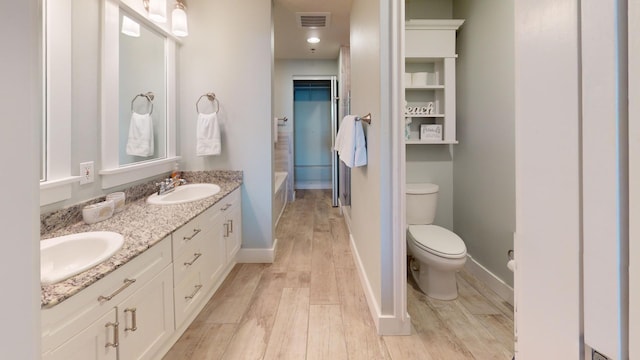 bathroom with toilet, hardwood / wood-style floors, vanity, and a bathtub