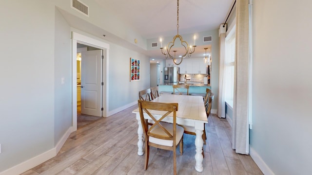 dining area with light hardwood / wood-style floors and a notable chandelier