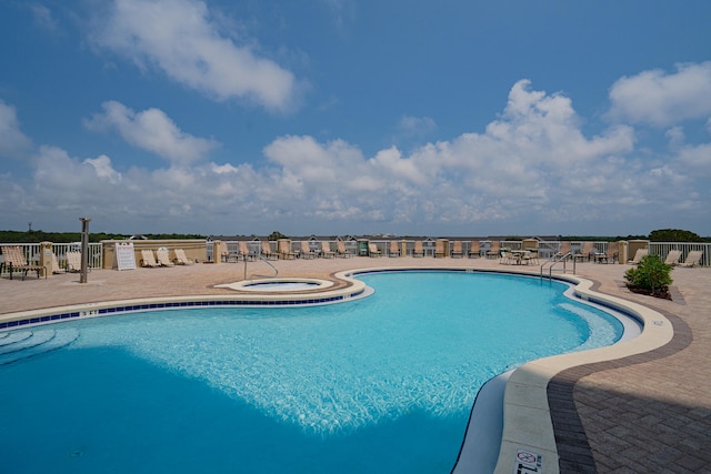 view of swimming pool with a hot tub and a patio