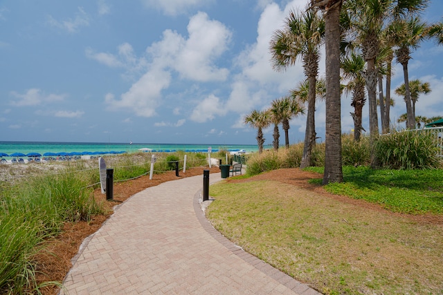 surrounding community with a view of the beach, a lawn, and a water view