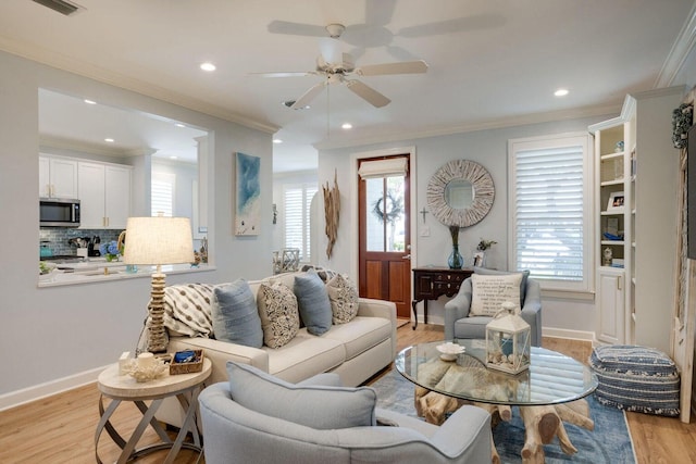 living room featuring ceiling fan, a wealth of natural light, crown molding, and light hardwood / wood-style flooring