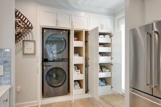 washroom with light wood-type flooring, ornamental molding, and stacked washer / drying machine